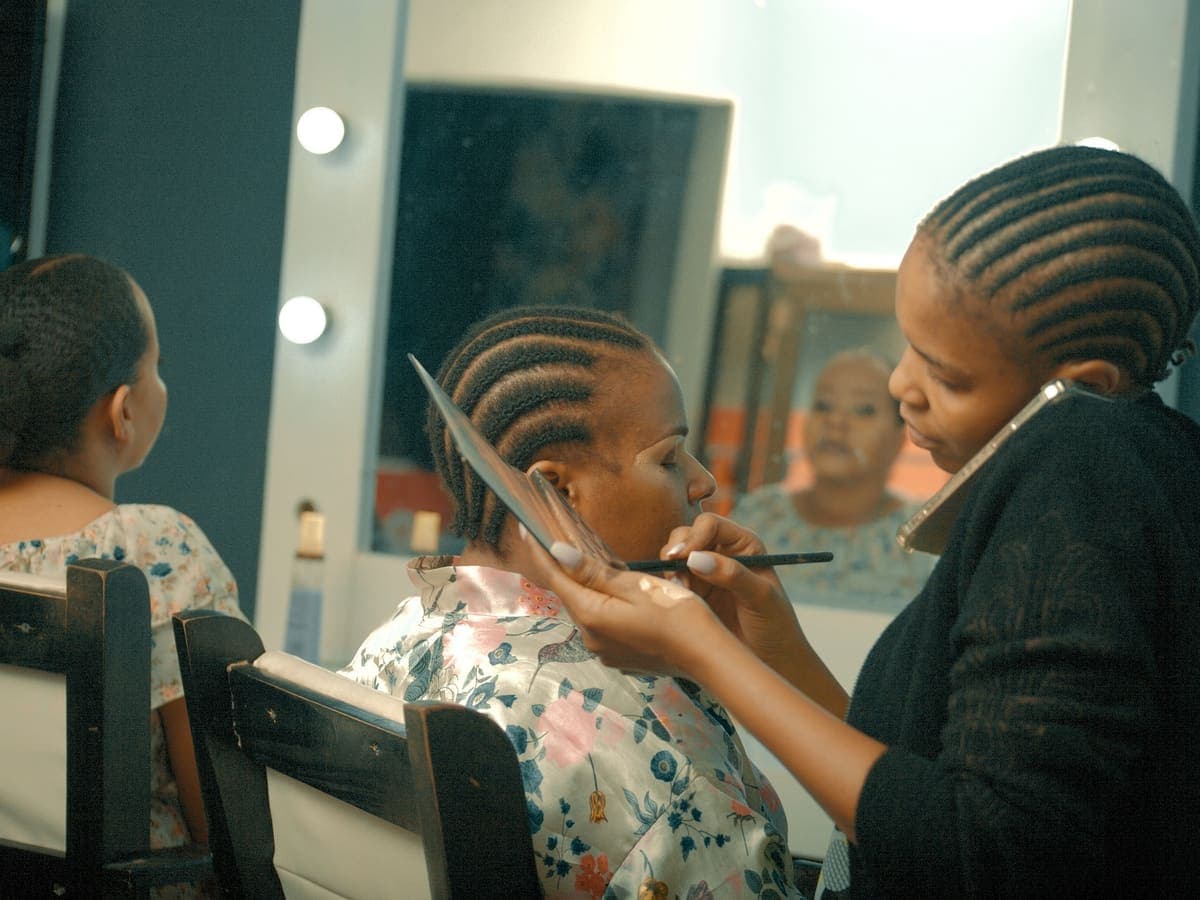 Makeup artist working with a client while managing a phone call